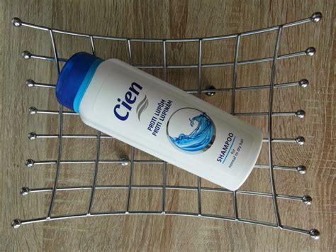 fľaša modrého šampónu Cien proti lupinám na poličke v kúpeľni