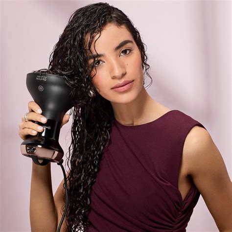 Žena sušiaca si kučeravé vlasy difuzérom