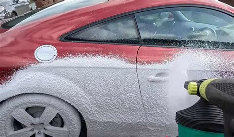 Detailný záber na umývanie karosérie auta s bohatou penou