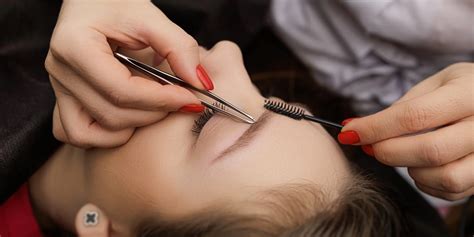 Muž si upravuje obočie pomocou hrebeňa a nožničiek