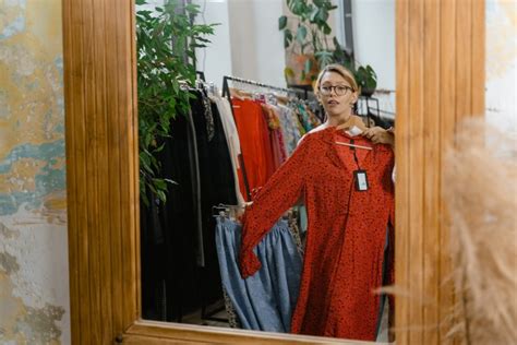 Žena skúša šaty pred zrkadlom s rôznymi typmi šiat na pozadí
