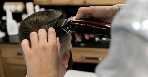 Barber strihajúci mužské vlasy v holičstve
