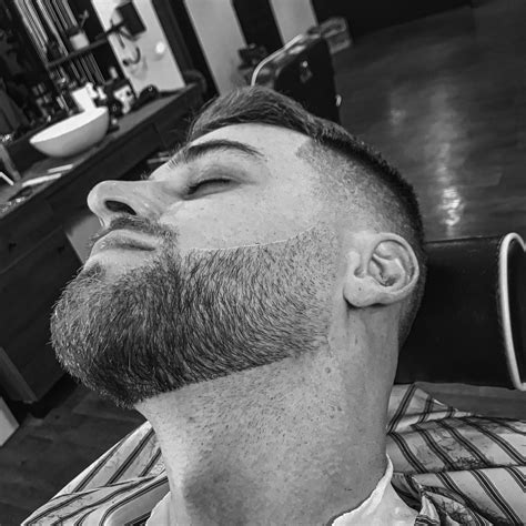 Muž v barbershope počas úpravy brady a vlasov