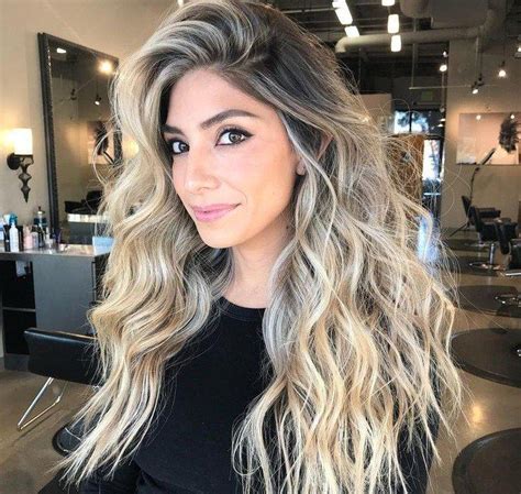 Detailný záber na proces aplikácie balayage štetcom na tmavé vlasy