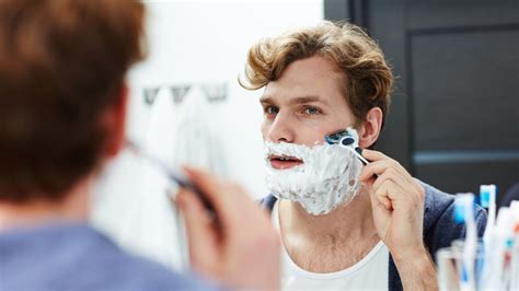 Muž pri holení tváre s penou na holenie