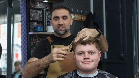 Barber vykonávajúci tradičné holenie krku horúcim uterákom