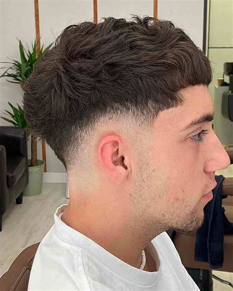 Muž s moderným, krátkym kučeravým účesom (crop taper fade)